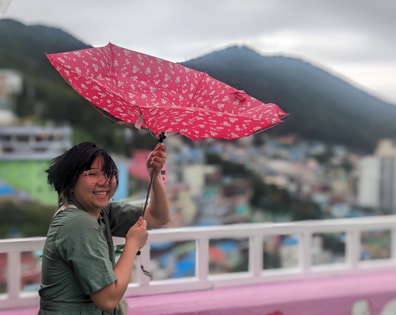 picture of Dalena standing outside on a windy day, with an umbrella that's been turned inside-out by the wind
